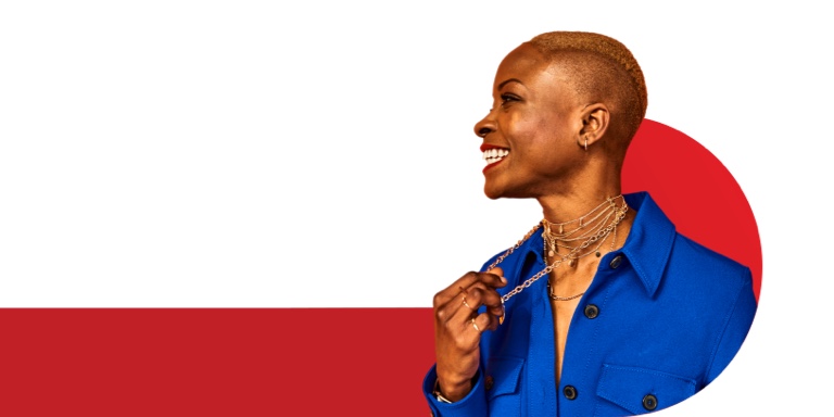 Confident African woman wearing gold necklaces, smiling as she looks to the left, holding one of her necklaces in her hand.