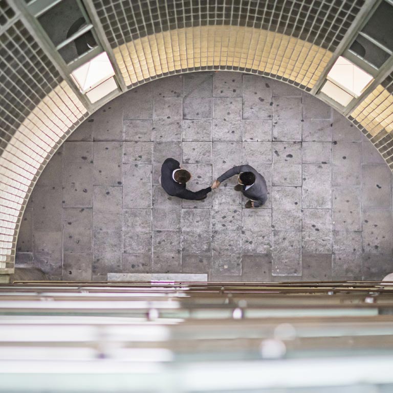 A top view looking down a round building with two men dressed in dark suits shaking hands.