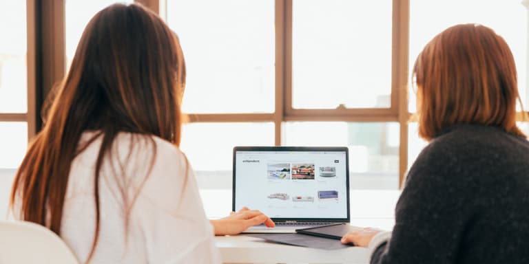 An employee consulting with a financial adviser while both view a laptop screen.