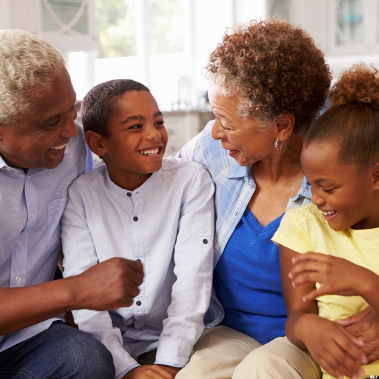Grandparents sitting and embracing their granddaughter and grandson.