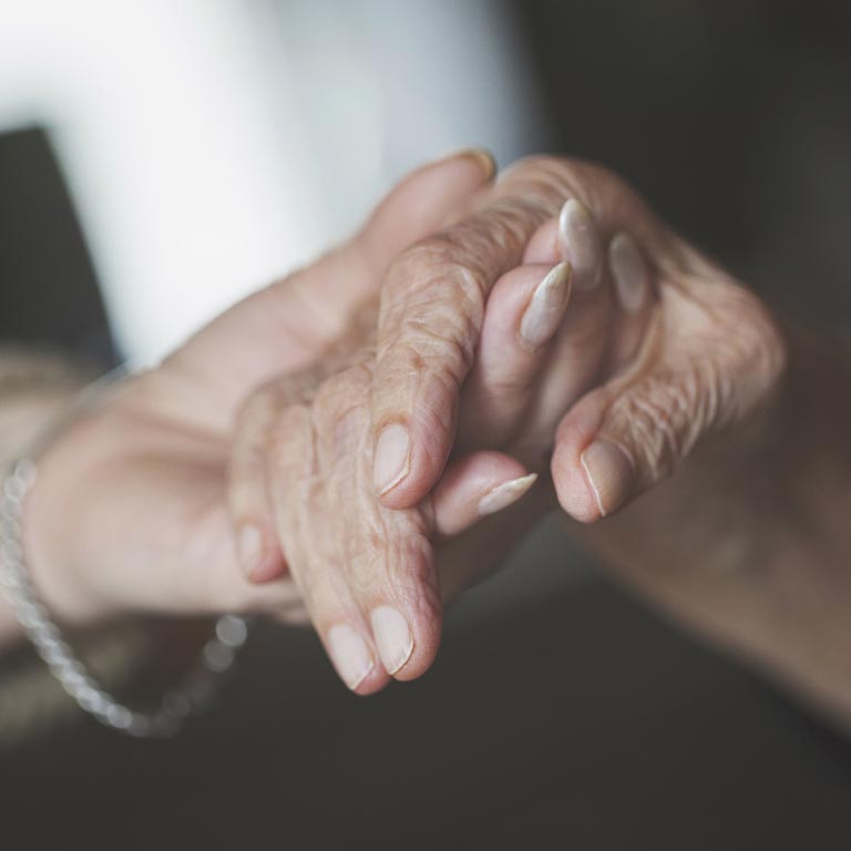 An elderly couple holding each others hands.