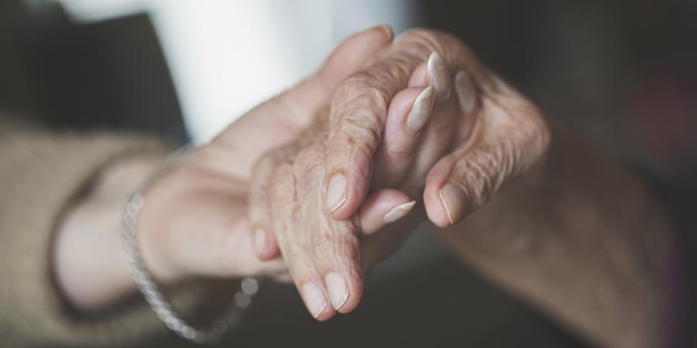 An elderly couple holding each others hands.