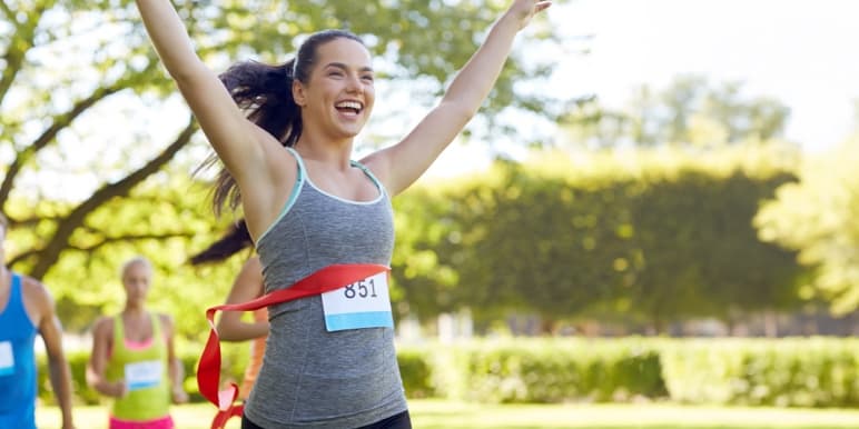 A happy young woman who has just crossed the finish line of a running race.