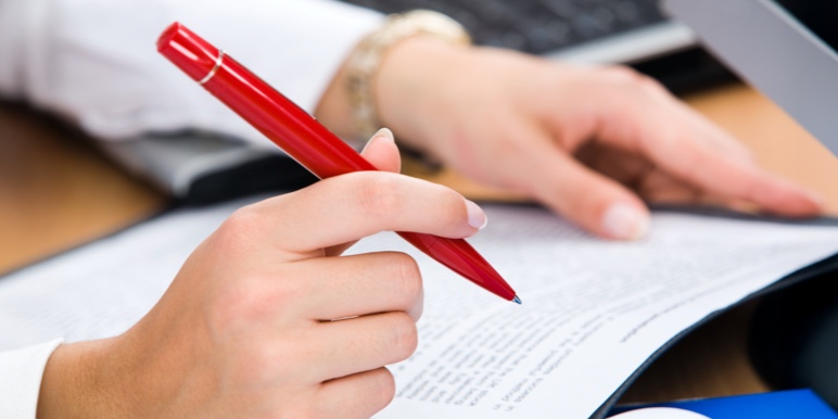 A hand view of a person holding a pen reading through all the costs of dying covered by estate protection. 