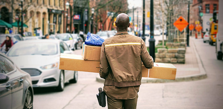 A courier carrying packages in a busy urban setting, symbolising the safe transportation of business goods.