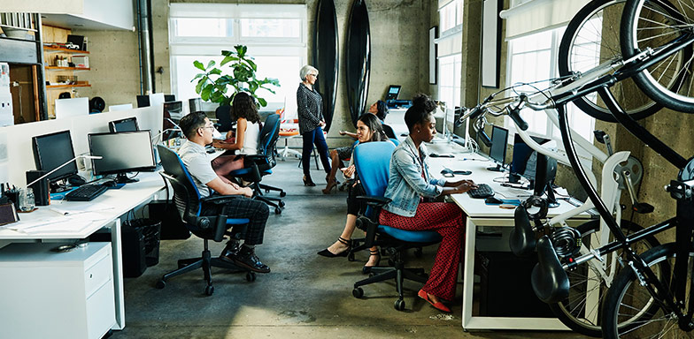 A contemporary open-plan office with employees working. The workspace includes essential office furniture, business equipment covered by insurance.