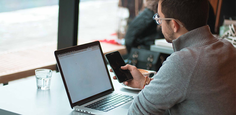 A man working remotely on a laptop in a café, representing the need for business all-risk insurance in South Africa to protect portable business assets.