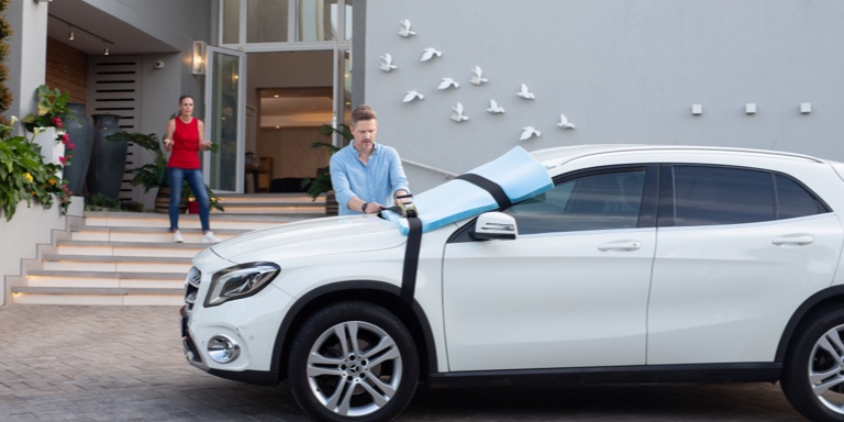 A father and his two young sons unpack the boot of their SUV.