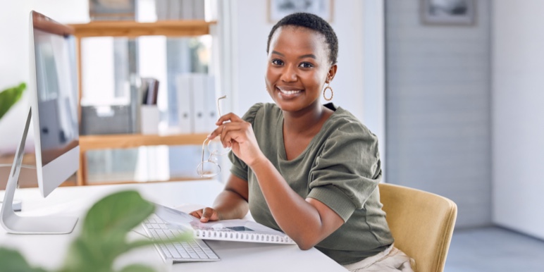 Lady sitting in front of her Mac desktop with a planner notebook as she works on her financial planning.