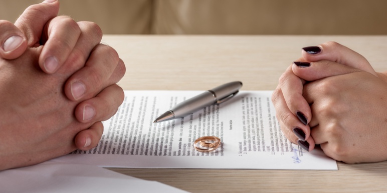 A man and woman sitting opposite each other, infront of divorce papers