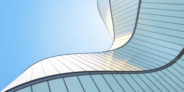 Low-angle view of futuristic modern architecture - a skyscraper of a corporate office building in a curved shape.