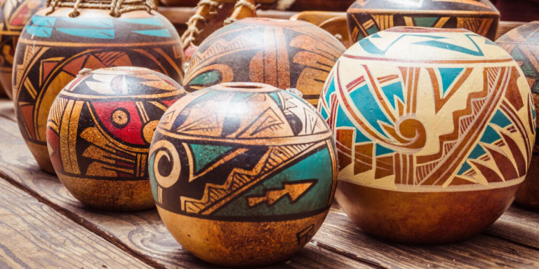 Many wooden pots with patterns in turquoise blue, cream, brown and black that are symbolic of the upcoming two pot retirement system. Your retirement savings will be split into 2 pots: a savings pot which you can withdraw from and a retirement pot.