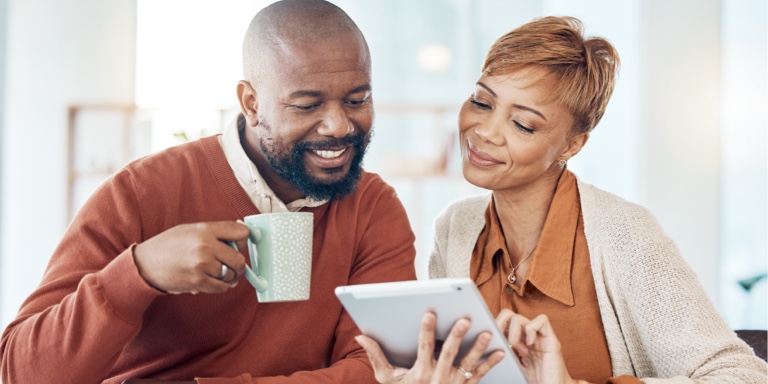 An established African couple doing research on the different annuity options available to them at retirement on a tablet, while having a cup of coffee.