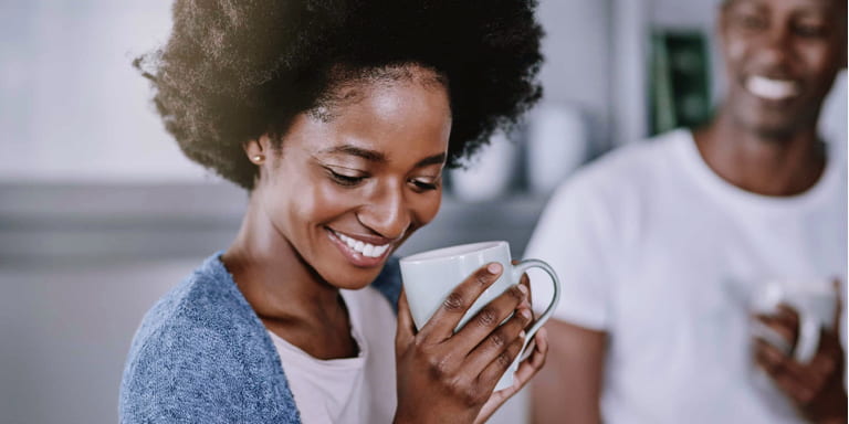 A young couple drinking their morning coffee in their kitchen in their home.