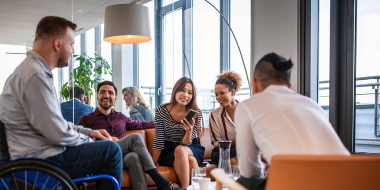 A man in a wheelchair sitting in an informal area chatting with a group of friends.