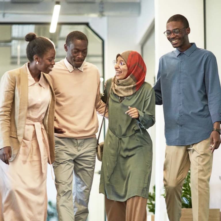 A group of 4 individuals walking and chatting about the advantages of employee benefits from Momentum Corporate.