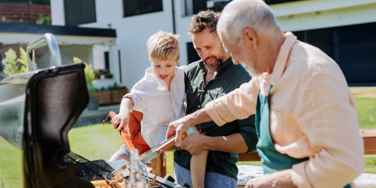 A grandfather, father, and son, braaing outdoors, representing lifelong saving and investment across life stages.