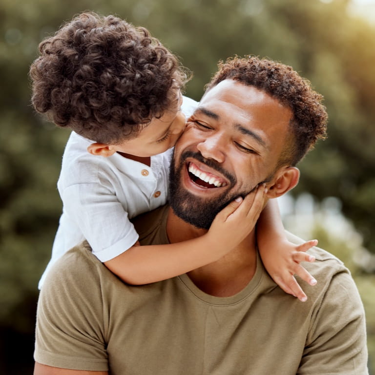 Son hugs father’s shoulders, representing strong family bonds and protected legacy, secured through a Trust.
