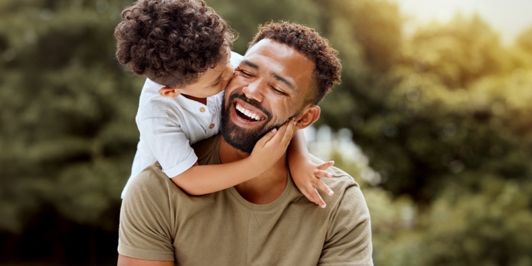 Son hugs father’s shoulders, representing strong family bonds and protected legacy, secured through a Trust.
