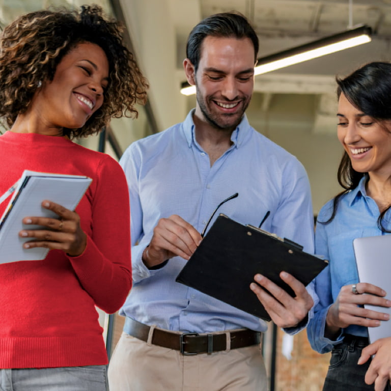 Three adults looking at a clipboard and smiling happily.