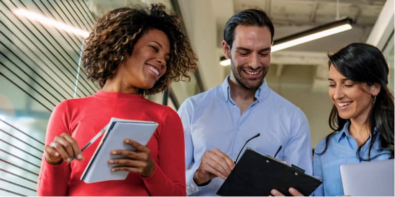 Work colleagues, two women and a man, walking and discussing work.