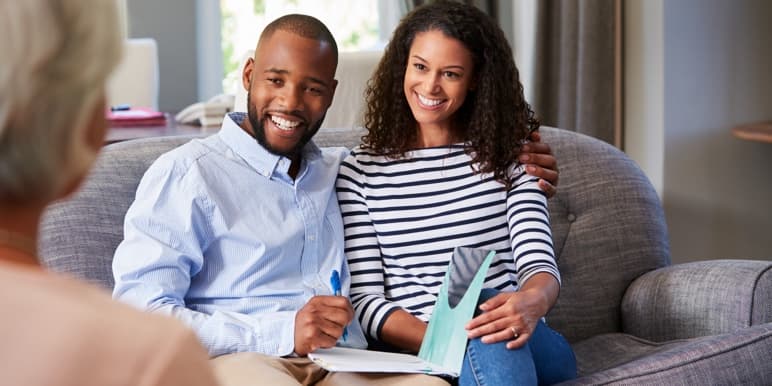A couple sitting on the couch in consultation with a financial adviser to get a new Momentum insurance policy.