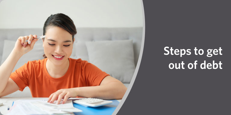 Woman in red shirt writing on paper in a video about steps to get out of debt.	
