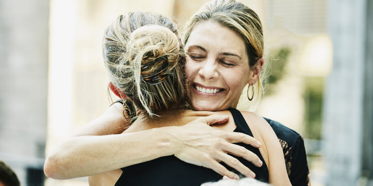 Two ladies hugging and smiling.