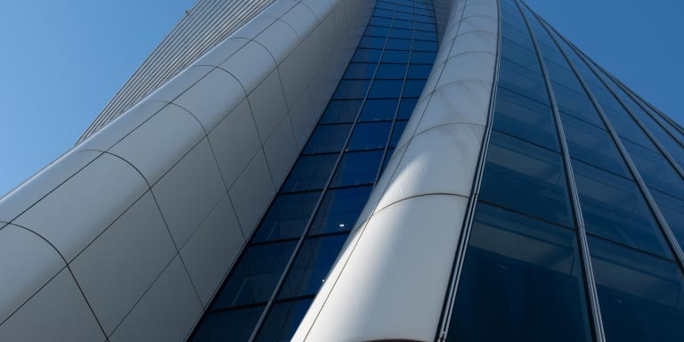 View of the Generali tower looking up from the ground where you can see the curvature of the building. 