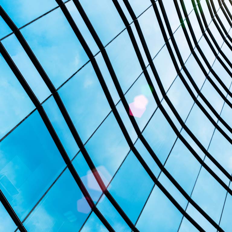 Low-angle perspective of a glass building with black lines.