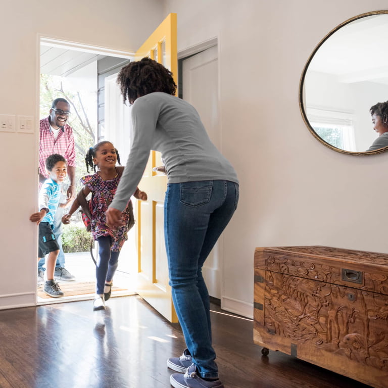 Dad with young son and daughter running happily to greet their mom. 
