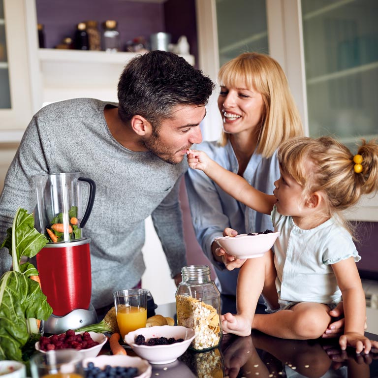 Family of 3 in the kitchen making a healthy smoothie for breakfast.