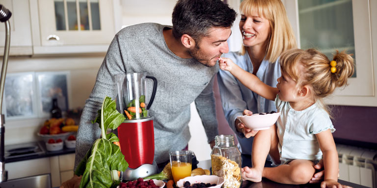 Family of 3 in the kitchen making a healthy smoothie for breakfast.
