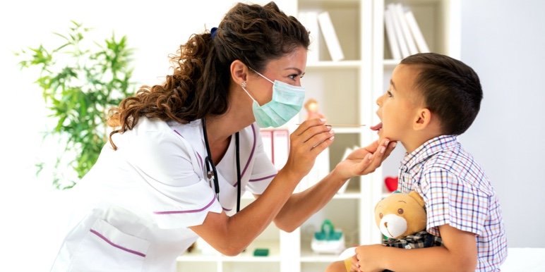Mom holds her baby son while a female doctor listens to the child's heartbeat with a stethoscope.