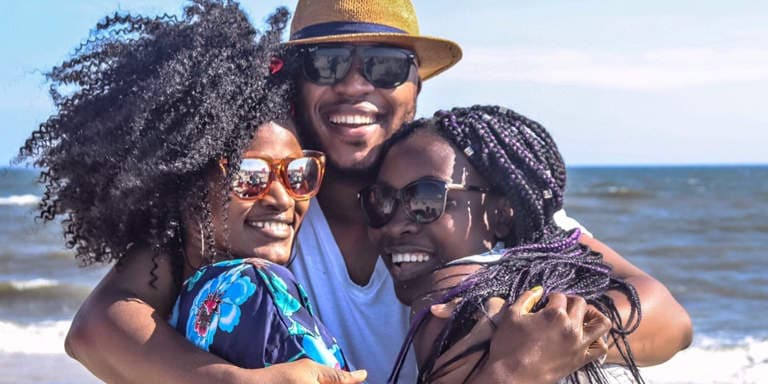 Three cheerful friends at the beach, laughing and smiling on a hot summers day.