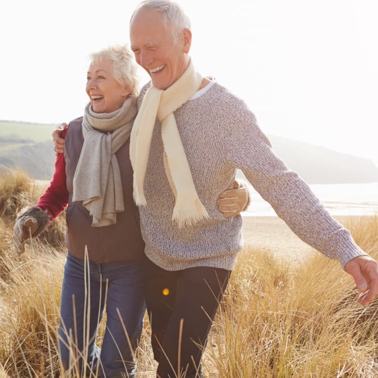 A content retired white couple, enjoying the winter, sunny outdoors, dressed in jeans, scarves and jerseys.