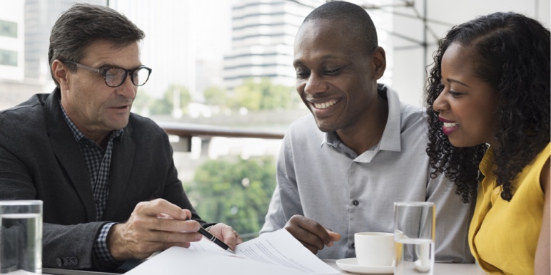 A young couple sitting with a financial adviser going through documents.