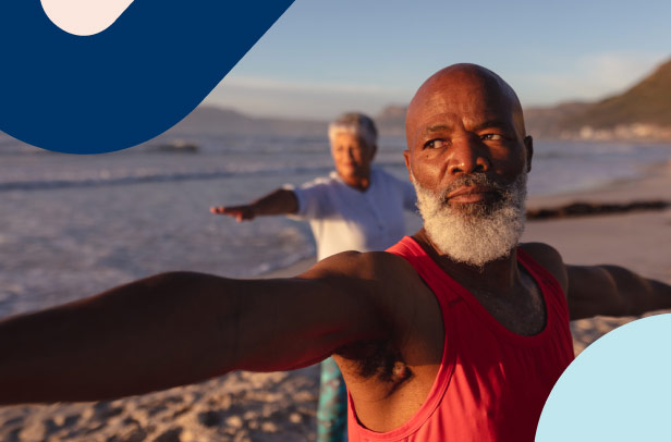 A retired man enjoying a yoga class on the beach with other participants.