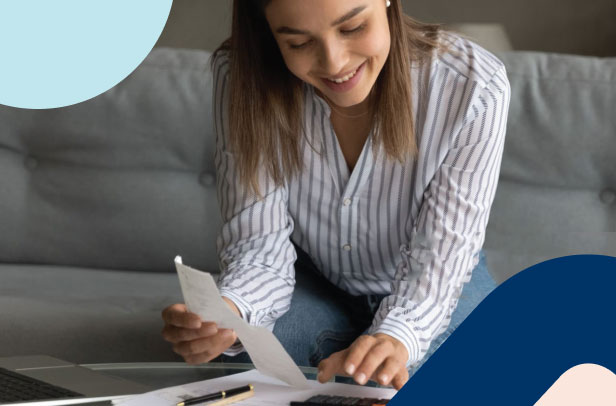 A young woman sitting on a couch with a paper and calculator, calculating her expected retirement funds in her retirement annuity when she retires.