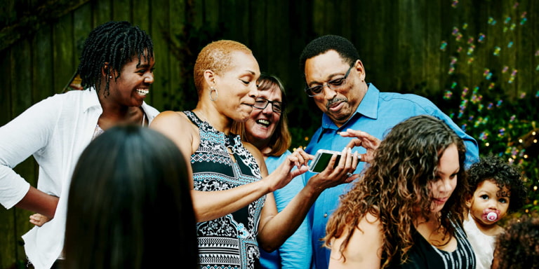 A group of people looking at a phone and smiling while walking together.