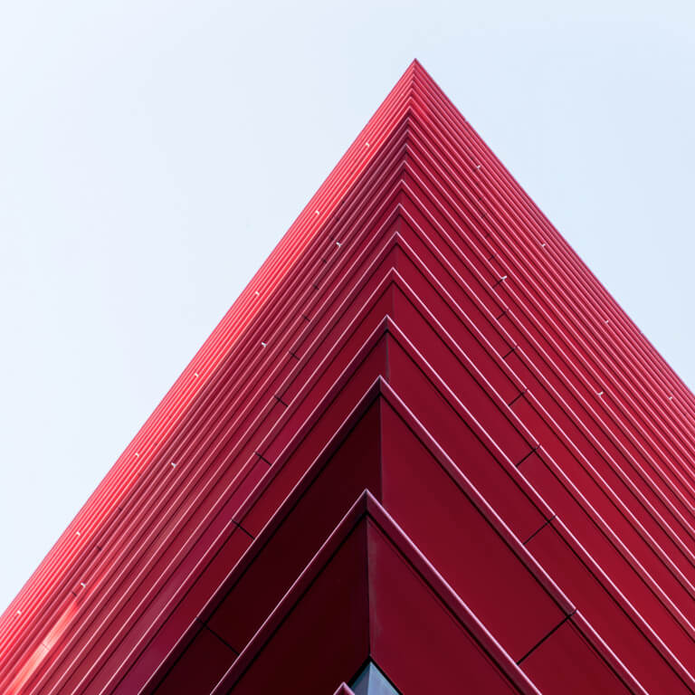 A red, futuristic high-rise office building with red balconies all around.