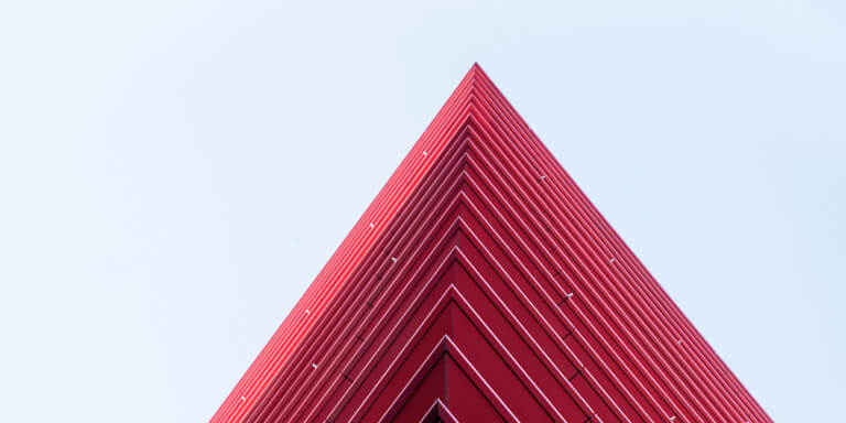 A red, futuristic high-rise office building with red balconies all around.