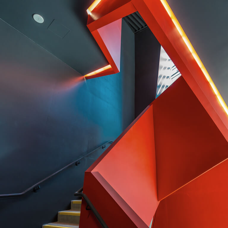 A staircase in a modern office building with an abstract, red and geometric balustrade.