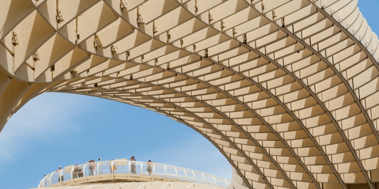 A side view of a modern curved architectural roof with a roof viewing deck encased with a glass barrier.