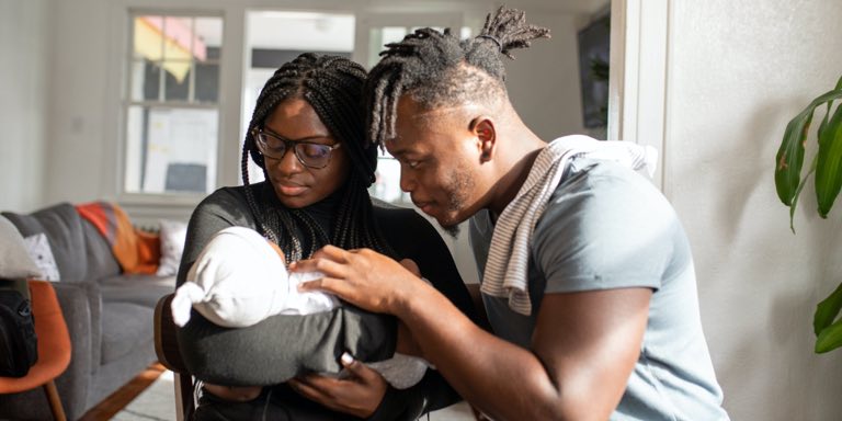 A young couple look at their newborn baby in the maternity wing at the hospital.