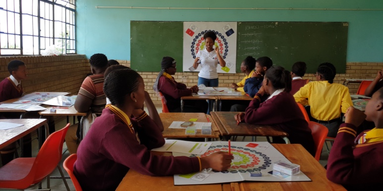 A classroom with learners facing front and looking attentively at their teacher.