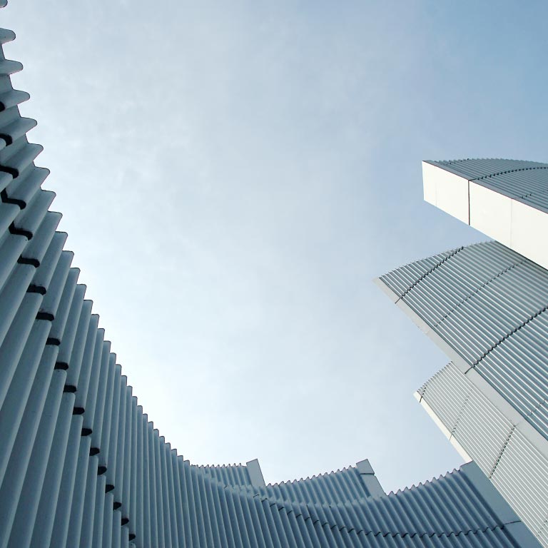 Low-angle view of an abstract architectural detail of a modern white building against a sky backdrop.
