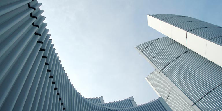 Low-angle view of an abstract architectural detail of a modern white building against a sky backdrop.