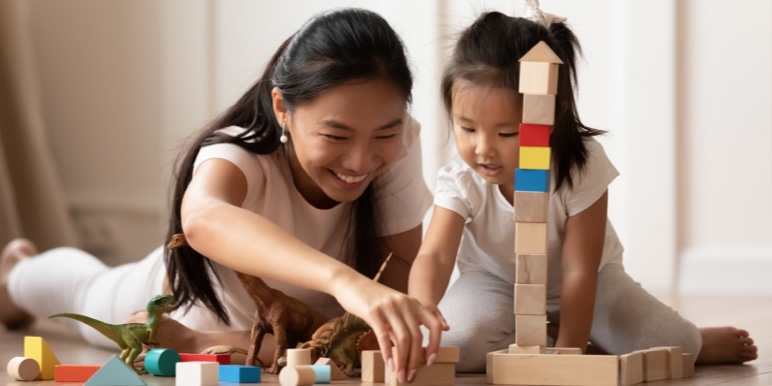 Mom and young child building a structure using different building blocks.