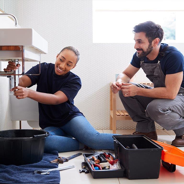 A couple fixing a bathroom sink.